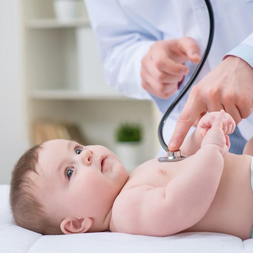 Baby laying on it's back while getting heart check by a doctor with a stethoscope