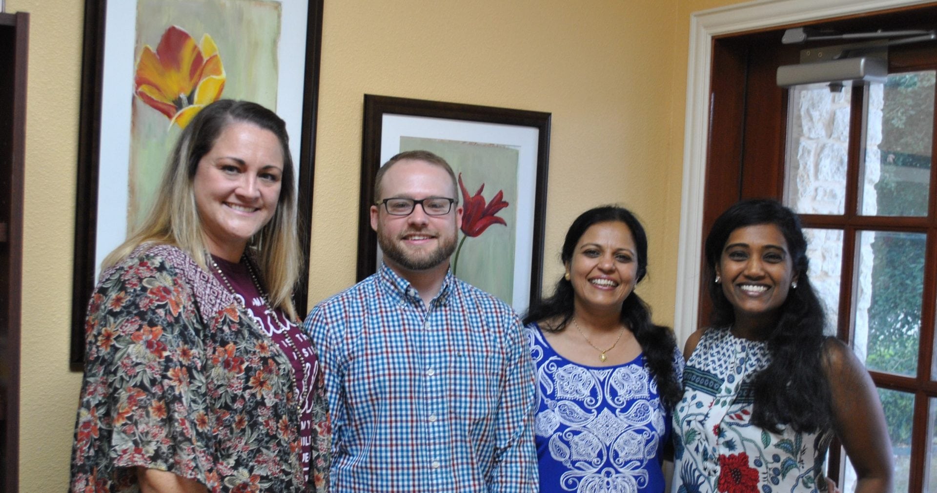 Provider Group Picture Four people standing in a room with a painting behind them.