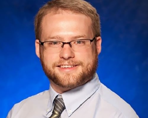 team4 A man with glasses and a beard wearing a shirt, tie and white shirt.